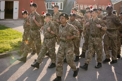 A group of teenagers in military uniform marching