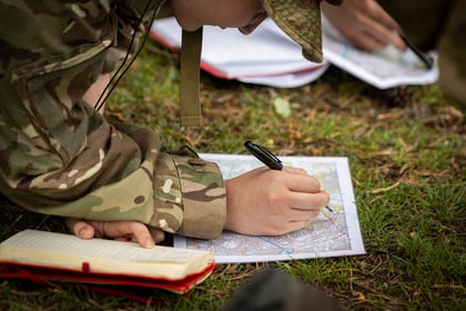 Cadet reading map and writing in a notebook