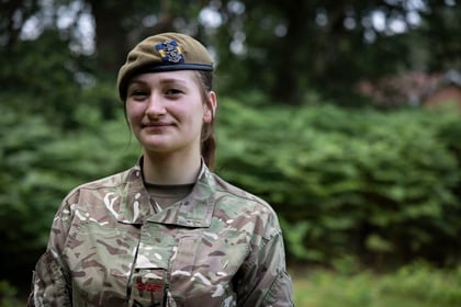 female cadet in military uniform in olive green beret facing the camera smiling