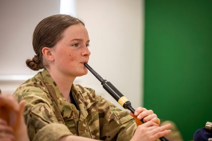 girl with brown hair learning to play the bagpipes by blowing in the reid