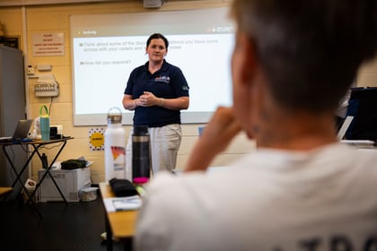 Lady in blue stood in front of a classroom of students presenting