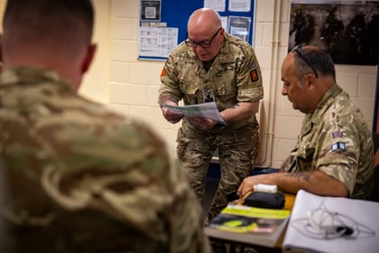 3 adults in military uniform involved in a group reading a task from a card