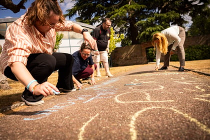 Adults drawing words on the floor with multicoloured chalk