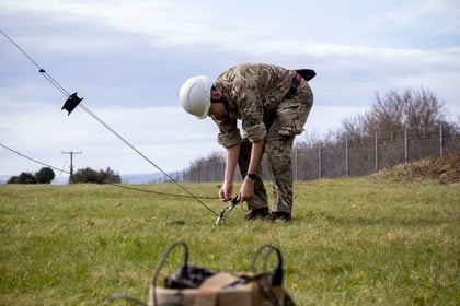 cadet bending over putting in a mast in a field