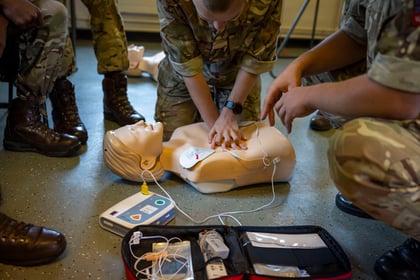 White CPR mannequin on the floor with cadets performing first aid on them