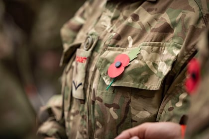 Cadet uniform with a red paper poppy for remembrance attached to the camouflage pocket.