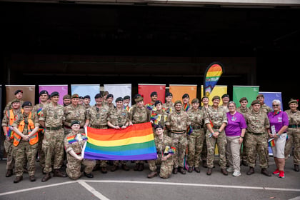 Cadets and adult volunteers pose with Pride coloured banners in the background