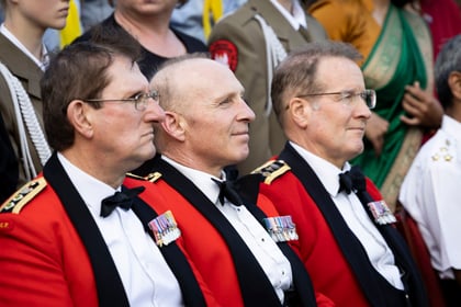 Senior cadet leadership team sits while waiting for photo dressed in uniform in red and black