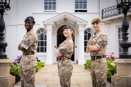 Three cadets from the International Exchange pose for a photo on the steps of Frimley Park Cadet Training Centre