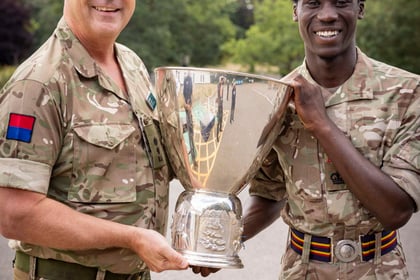 ACF winner of the Champion Cadet Competition stands with his trophy being held by a senior officer during the parade