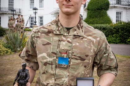 Winner of the Champion Cadet Competition stands with smaller trophy and his coin
