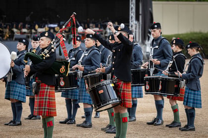 Ceremonial cadets in a colourful military band playing instruments including drums and bagpipes during a parade in central London.