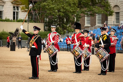 Cadets in traditional military attire marching and playing instruments at a grand musical event at Horse Guards Parade.
