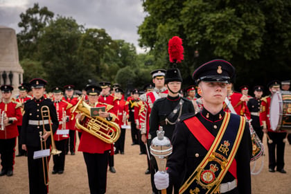 Cadets in traditional military attire marching and playing instruments at a grand musical event at Horse Guards Parade