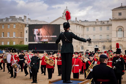 Cadets dressed in ceremonial attire play instruments while marching at Horse Guards in London.