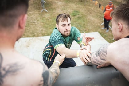 Adult climbing over a wall with the help of others