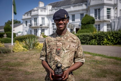 Male cadet stands with his trophy in front of the Frimley Park building