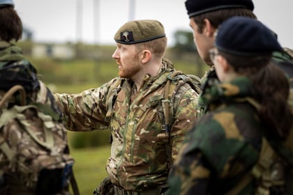An adult volunteer speaks to other cadets