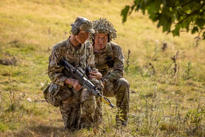 Cadets in a fieldcraft exercise with one male cadet looking at the camera