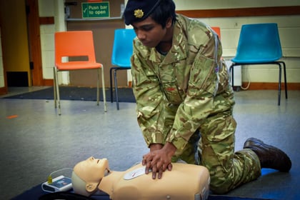Mixed race cadet doing CPR on a dummy during first aid training