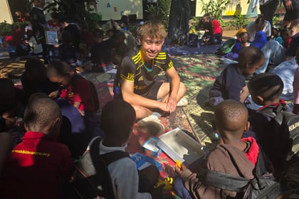 Male cadet sits on the floor while playing games with young kids from an orphanage