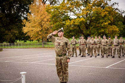 Cadet saluting with autumn leaves on the trees in the background on the parade