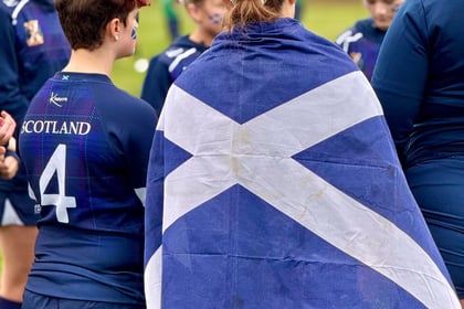 The back of the Scottish cadet with a flag draped over her shoulders