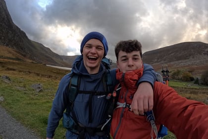 Two male cadets smile for a selfie with Welsh mountains behind them