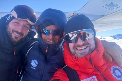 Jordan Wylie poses with two other explorers in front of the plane