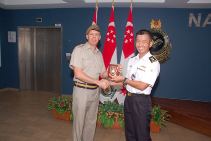 Colonel James Morris in Cyprus stood presenting a gift in front of some flags.