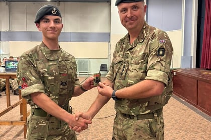 Colonel Paul Deakin, tall man stood in military uniform handing something and shaking hands with a cadet in military uniform