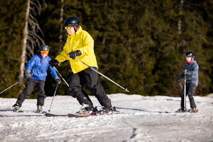 Group of adult volunteers pose on ski slope while learning to ski in Bavaria
