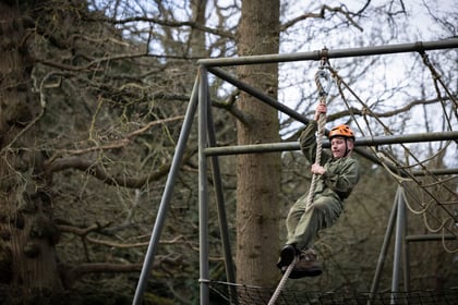 A male cadet slides down the rope on the obstacle course