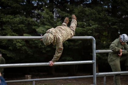 The brigadier jumps over the bars on the Master Cadet obstacle course