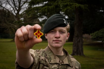 Cadet holds up his Master Cadet badge
