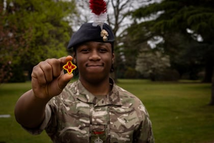 Male cadet holds up his Master Cadet badge