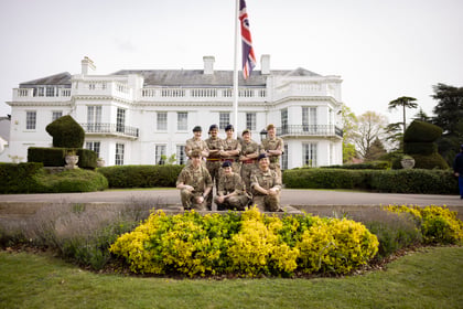Cadets pose for a photo with a white building in the background