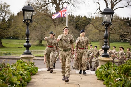 Cadets march up the stairs of CTC Frimley Park with Union Jack flag in the background