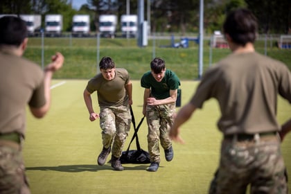 Cadets pull heavy bag across a sports field