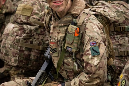 Male cadet wears a camo helmet and holds a weapon