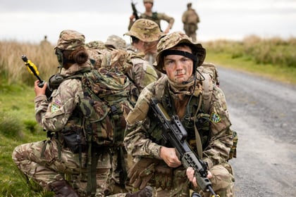 A team of cadets kneel on a gravel road during fieldcraft exercise at Cadet Cambrian Patrol 2026