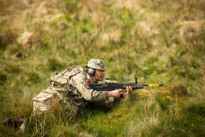 Female cadet lies on the ground during fieldcraft exercise at Cadet Cambrian Patrol 2026