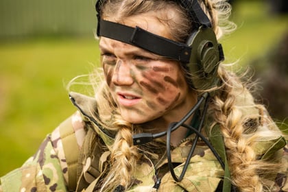 Female cadet wears camo cream on her face during fieldcraft exercise at Cadet Cambrian Patrol 2026