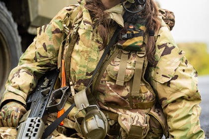 Female cadet sits next to a vehicle with headset around her head