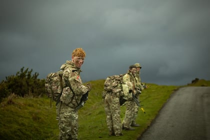 Cadet with ginger hair looks back at the camera with dark rain cloud in the sky