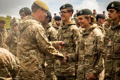 Male cadets shake hands with an adult instructor while receiving a medal