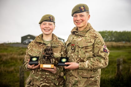 Female and male cadet smile while holding their medals and trophy