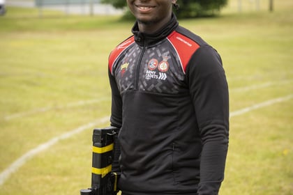 Male cadet holds weapon at his site while dressed in a black and red jumper