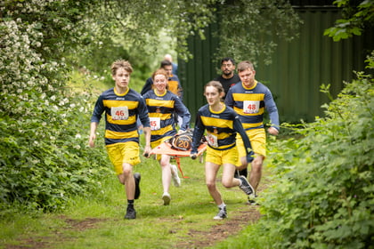 Cadet team dressed in green and yellow run with a stretcher