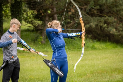 Female cadet holds a bow and arrow at an archery exercise